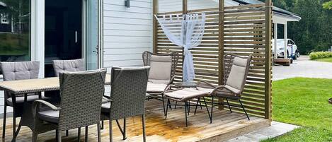 An outdoor patio with wicker furniture, a covered seating area, and a wooden deck.