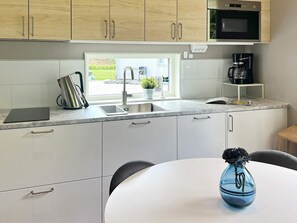 A modern kitchen with a built-in microwave, a coffee maker, and a sink. - 4 Star Holiday Home in Ljungby (Ljungby)