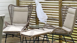 A set of wicker chairs with cushions, arranged around a small glass table on a wooden deck. - 4 Star Holiday Home in Ljungby (Ljungby)