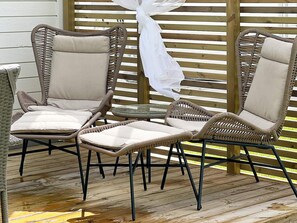 A set of wicker chairs with cushions, arranged around a small glass table on a wooden deck. - 4 Star Holiday Home in Ljungby (Ljungby)