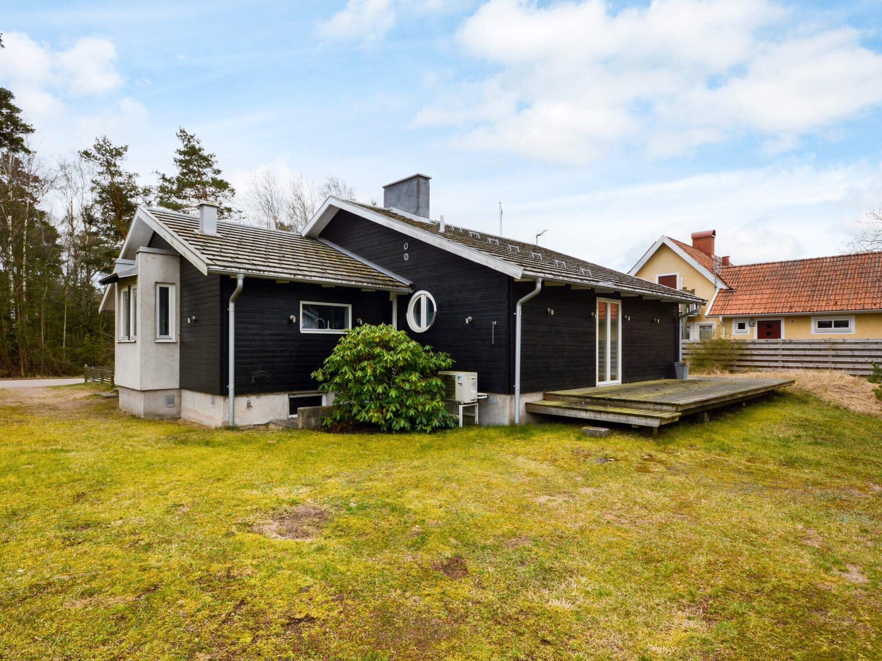 A two-story house with a dark exterior, a small porch, and a grassy yard.