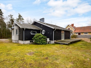 A two-story house with a dark exterior, a small porch, and a grassy yard. - 7 Person Holiday Home in Mellbystrand (Mellbystrand)
