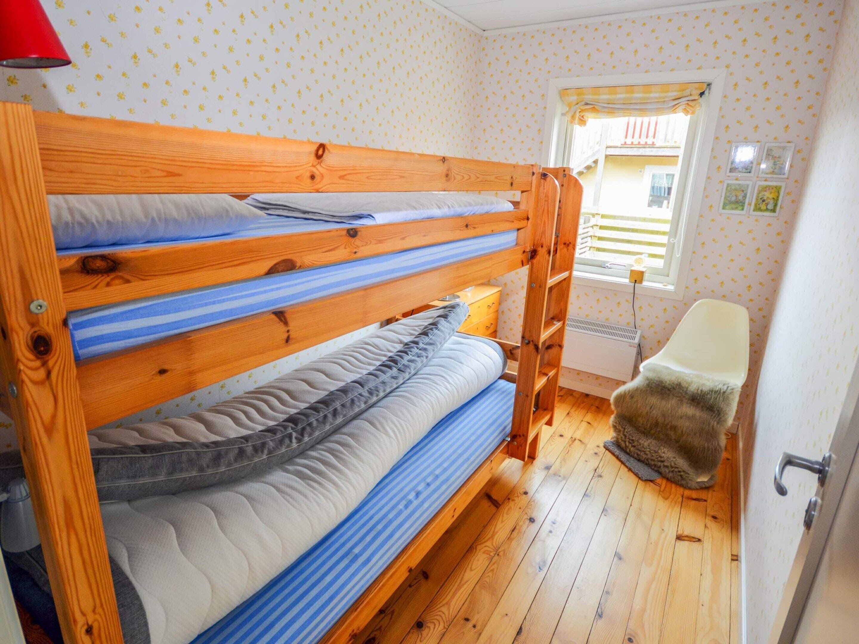 A bunk bed room with a wooden ladder, a small chair, and a radiator.