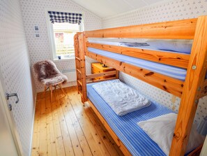 A bunk bed with a wooden frame and blue bedding, a small chair, and a window with a checkered curtain. - 7 Person Holiday Home in Mellbystrand (Mellbystrand)