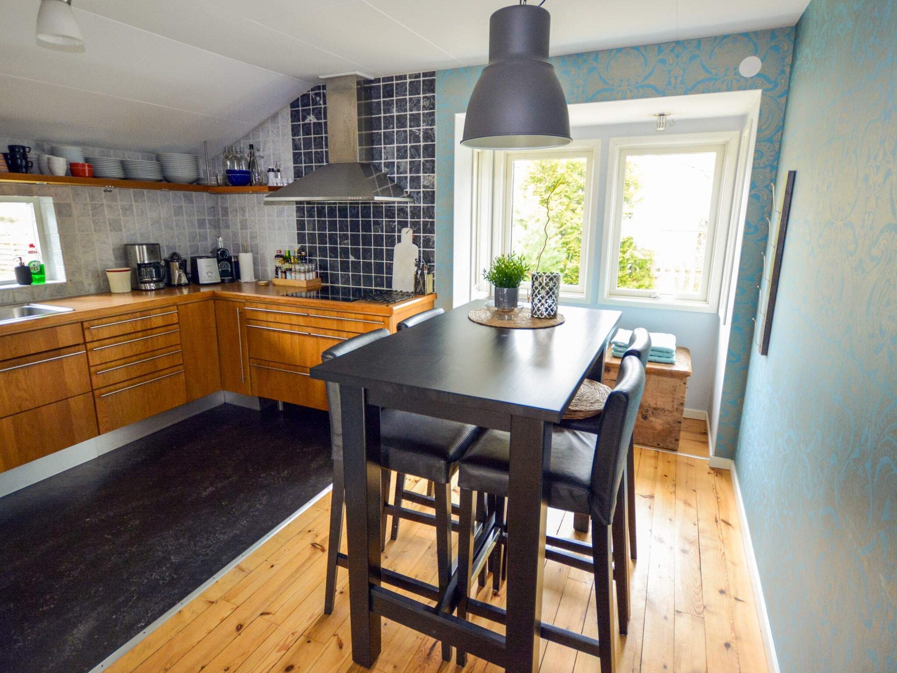 A kitchen with wooden cabinets, a black countertop, and a black pendant light.