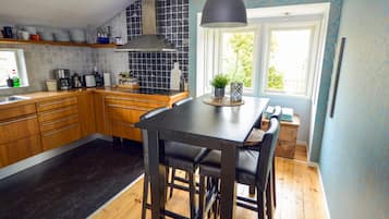 A kitchen with wooden cabinets, a black countertop, and a black pendant light.