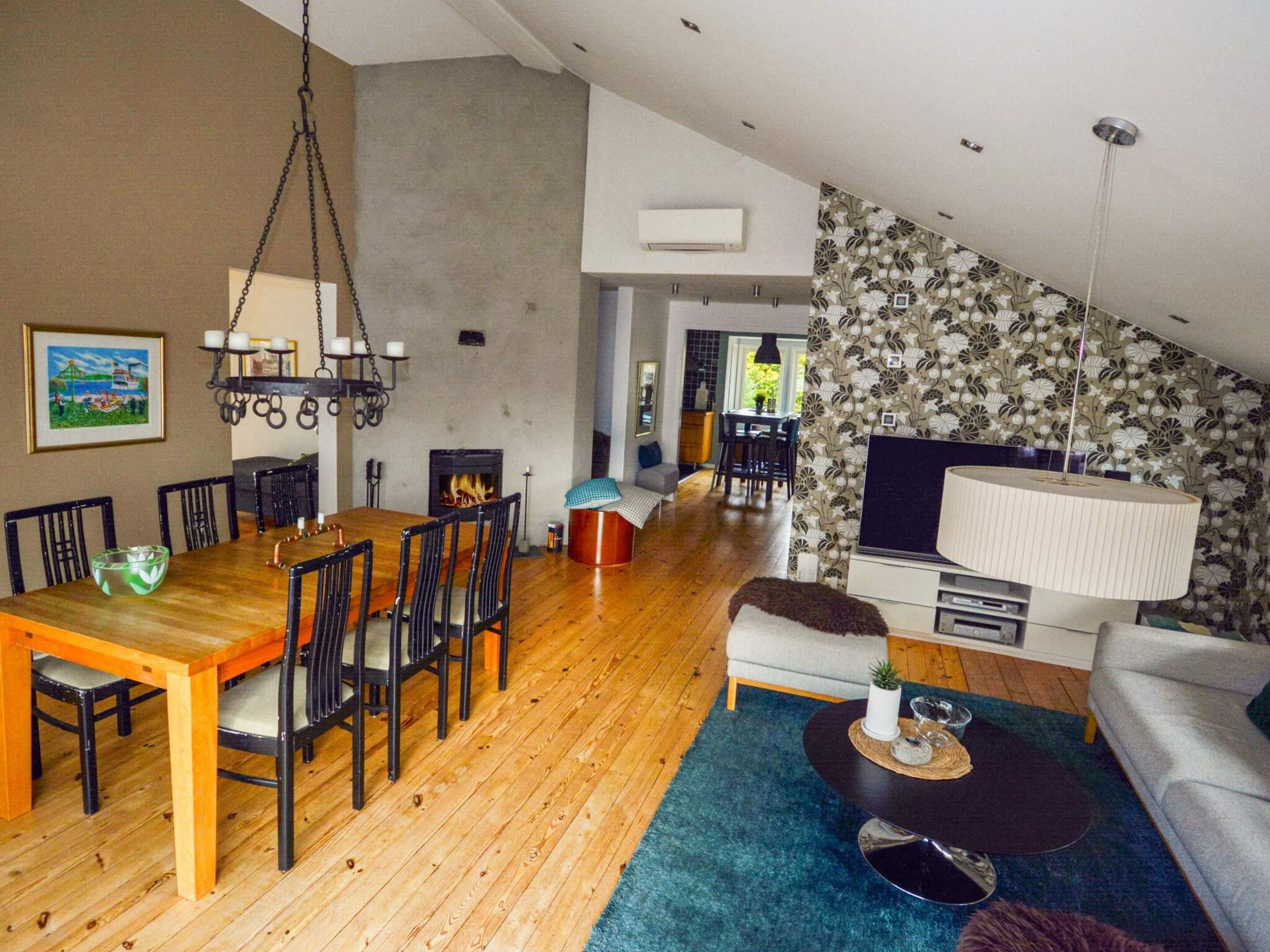 A modern living room with a dining area, a fireplace, and a TV.