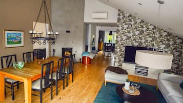 A modern living room with a dining area, a fireplace, and a TV.