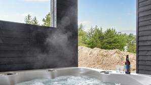 Ein Whirlpool mit Flasche und Gläsern, umgeben von einer Holzterrasse und Bäumen.