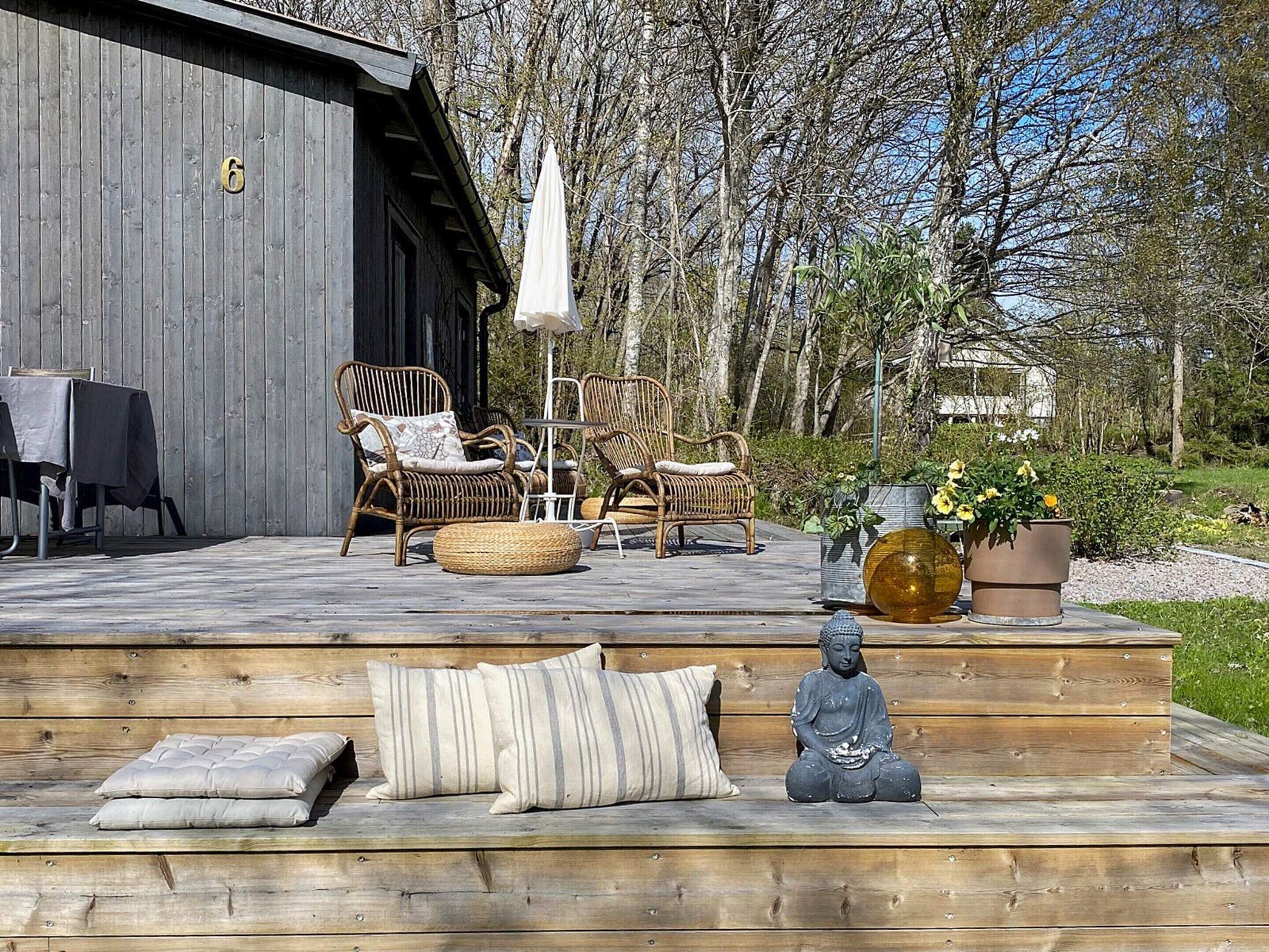 An outdoor seating area with wicker furniture, a Buddha statue, and potted plants.