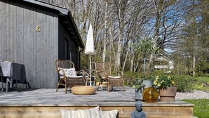 An outdoor seating area with wicker furniture, a Buddha statue, and potted plants. - 6 Person Holiday Home in Herrang (Herräng)