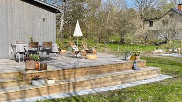 A wooden deck with outdoor furniture, a covered seating area, and a stone sculpture.