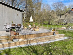 A wooden deck with outdoor furniture, a covered seating area, and a stone sculpture.