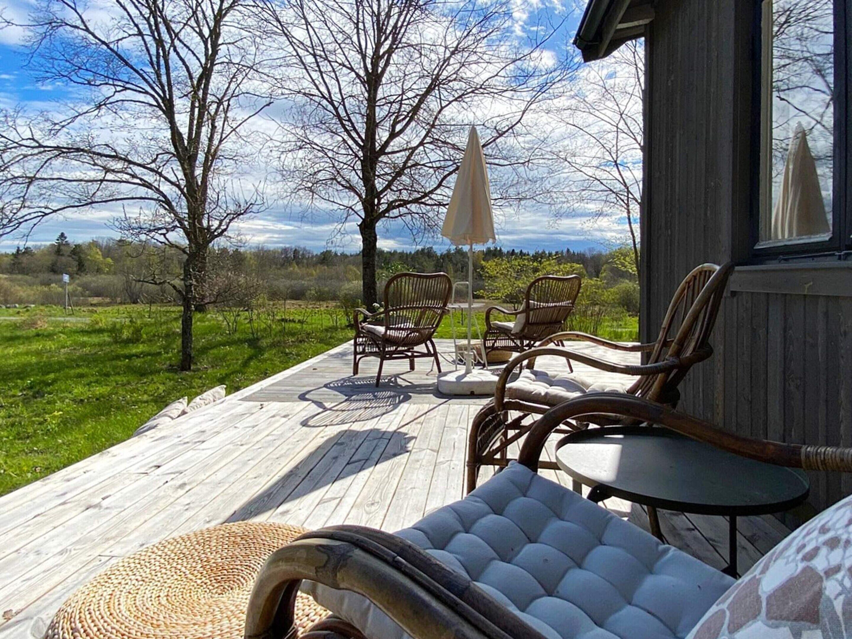 A wooden deck with wicker furniture and a view of the landscape.