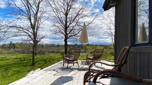 A wooden deck with wicker furniture and a view of the landscape. - 6 Person Holiday Home in Herrang (Herräng)