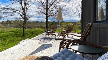 A wooden deck with wicker furniture, a table, and chairs.