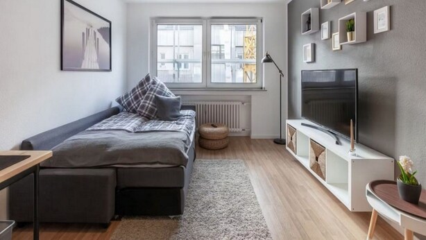 A modern, well-lit bedroom with a bed, a TV, and a window with a view of the city. - Modern Apartment Fully and High Quality (Heilbronn)