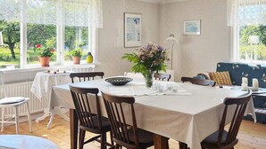 A dining area with a round table, chairs, a vase with flowers, and a sofa. - 5 Star Holiday Home in Urshult (Urshult)