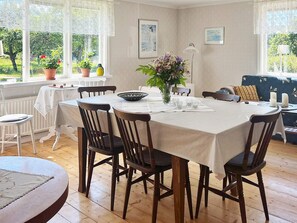 A dining area with a round table, chairs, a vase with flowers, and a sofa. - 5 Star Holiday Home in Urshult (Urshult)