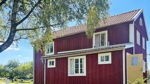 A red wooden house with a porch, a table, and chairs outside. - 5 Star Holiday Home in Urshult (Urshult)