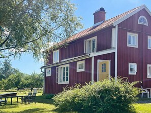 A two-story red building with multiple windows, a chimney, and a door. - 5 Star Holiday Home in Urshult (Urshult)