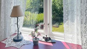 A window with lace curtains, a table with a lamp, a small potted plant, and a decorative item. - 5 Star Holiday Home in Urshult (Urshult)