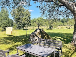 A park bench under a tree with a picnic table nearby. - 5 Star Holiday Home in Urshult (Urshult)