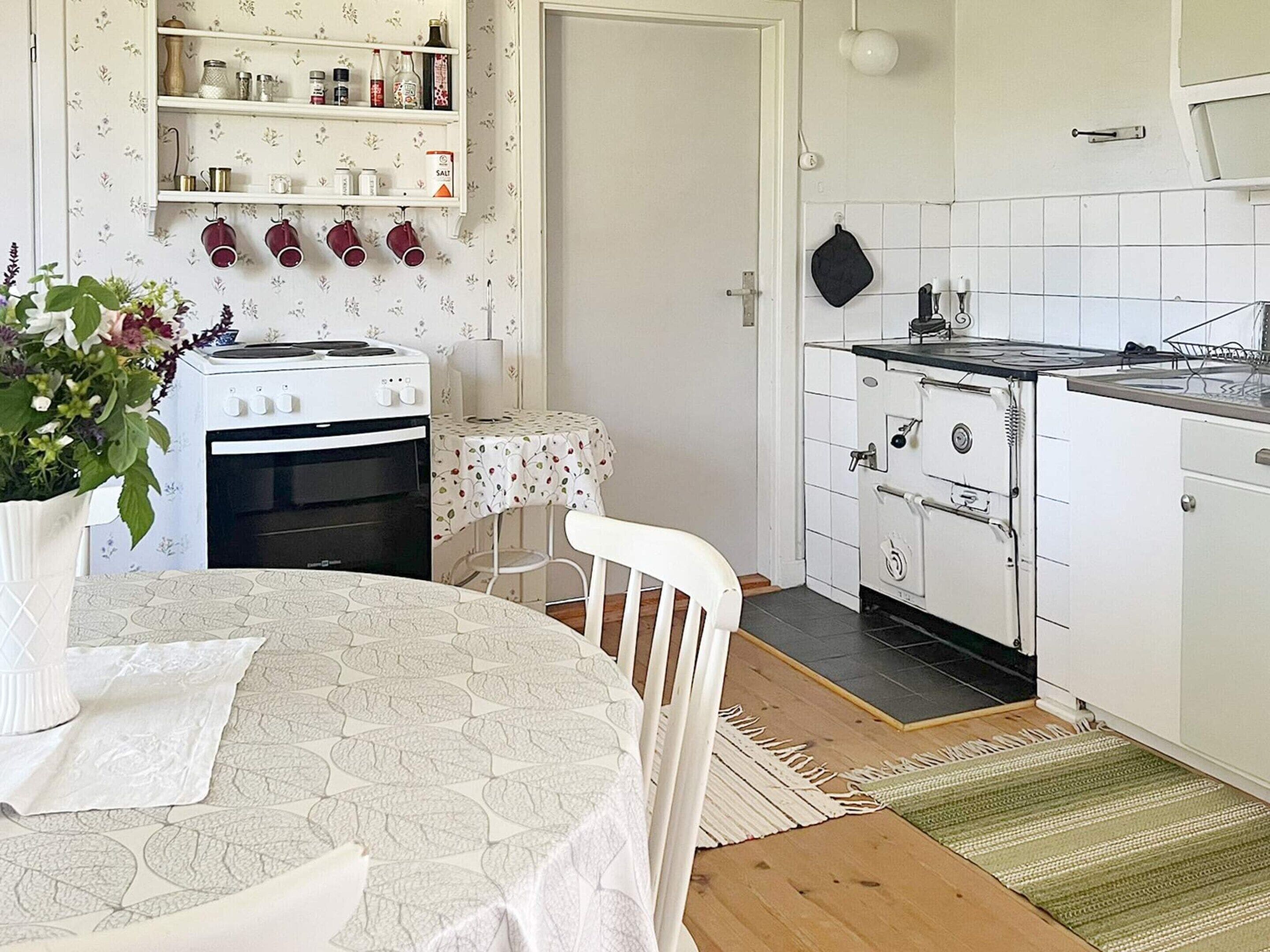 A kitchen with a white stove, oven, and a small table with a floral tablecloth.