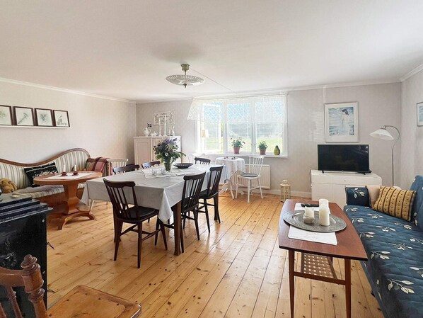 A well-lit living room with a dining area, a sofa, a television, and a fireplace. - 5 Star Holiday Home in Urshult (Urshult)