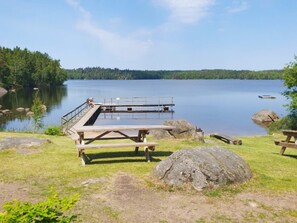 A lakeside picnic area with a wooden deck, picnic tables, and a dock extending into the water. - 4 Star Holiday Home in Karlskrona (Karlskrona)
