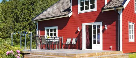 A red house with a porch, steps, and a table with chairs.