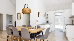Une cuisine moderne avec des meubles blancs, une table à manger en bois et des chaises grises.