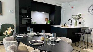 Un espace repas moderne avec une table noire dressée pour six personnes, entourée de chaises grises à revêtement.