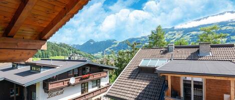 Un edificio de estilo chalet con balcón de madera, un restaurante llamado "Banana Bistro" y vistas a las montañas al fondo.