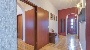 A hallway with wooden doors, a tiled floor, and a wall with framed pictures. - Holiday apartment near the beach (Pješćana Uvala)