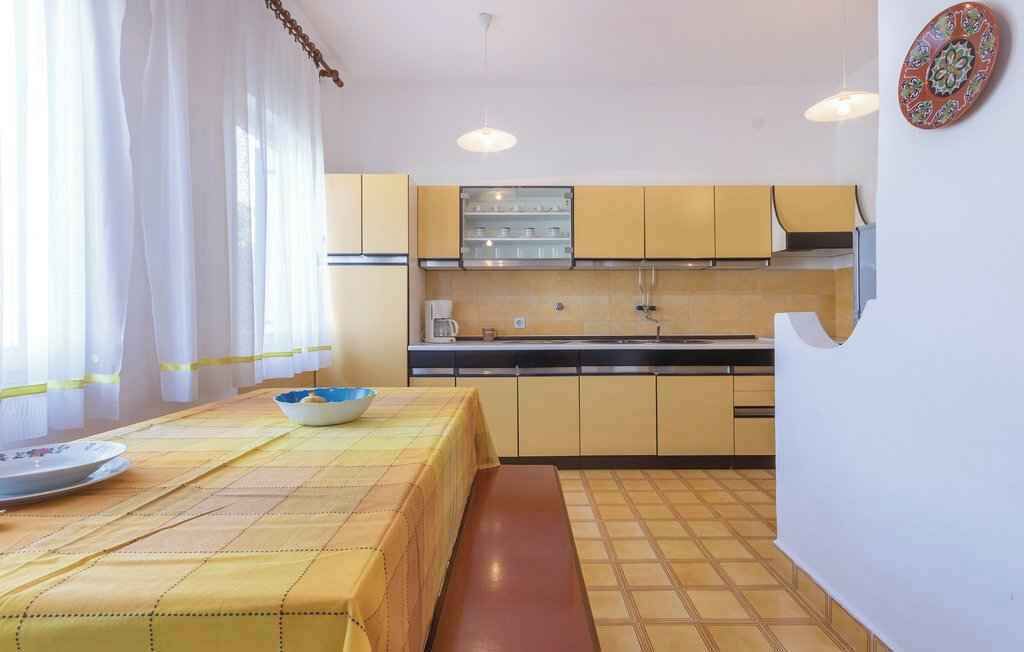 Una cocina compacta con armarios amarillos, una mesa de comedor con mantel amarillo y un banco.