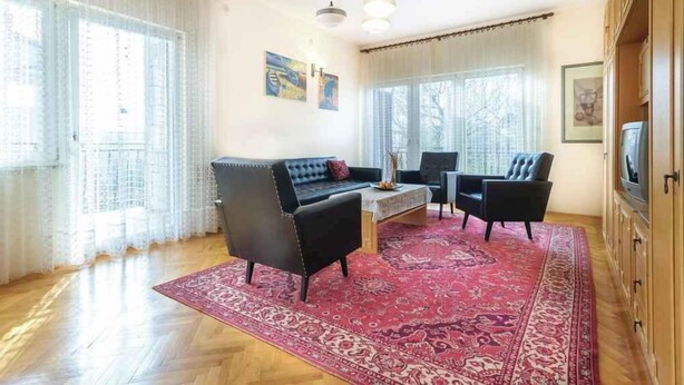 A living room with a sofa, two armchairs, a coffee table, and a red patterned rug. - Holiday apartment near the beach (Pješćana Uvala)