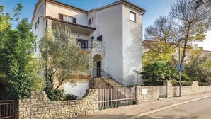 A two-story building with a stone wall and a metal fence in front. - Holiday apartment near the beach (Pješćana Uvala)