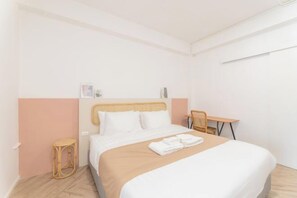 A hotel room with a bed, a small table, a chair, and a wall-mounted shelf. - Evergreen Apartment by Beginning with, 3Br in Heart of Nimman (Chiang Mai)