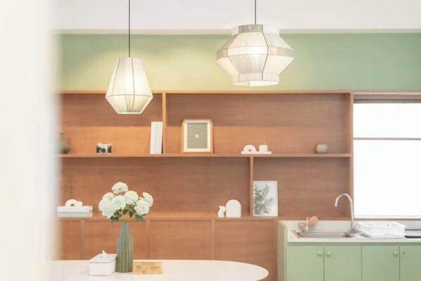 Una cocina moderna con estantes de madera, encimera blanca y un jarrón con flores.
