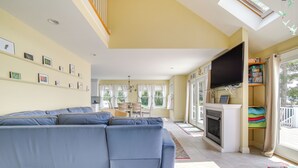 Una sala de estar con un sofá modular, una chimenea, un televisor y un ventanal con cortinas.