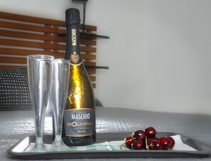 A bottle of Maschio wine, a glass, and a plate with cherries on a tray. - b&Baldo Vatican (Rome)
