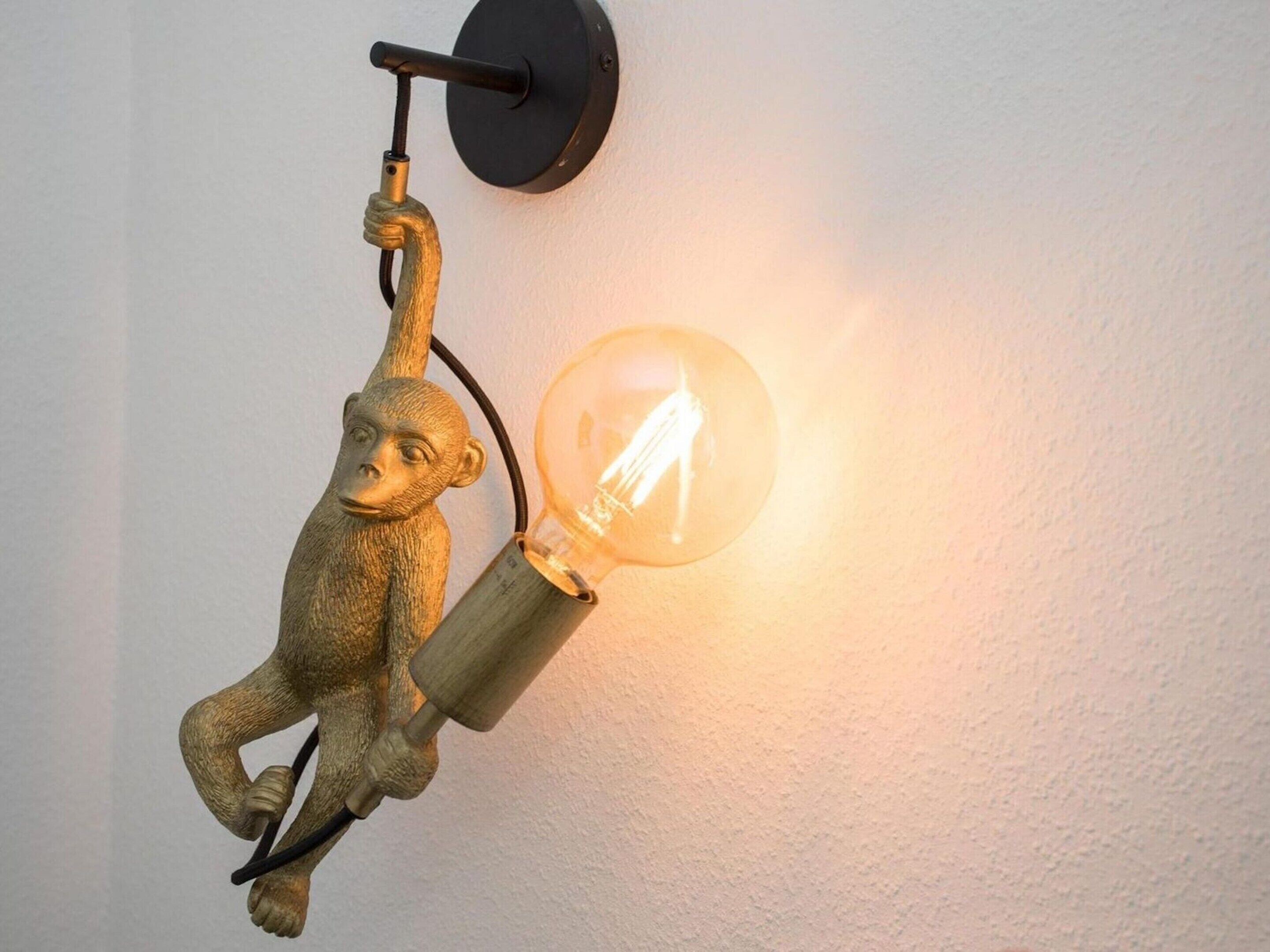 A wall-mounted light fixture with a monkey design and a clear glass bulb.