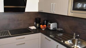 A modern kitchen with a black countertop, stainless steel sink, and white cabinets. - Klasse Apartment mit Balkon St. Anton am Arlberg (Sankt Anton am Arlberg)