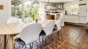 A modern kitchen with white cabinets, a wooden dining table, and two pendant lights. - 4 Star Holiday Home in Hals (Hals)