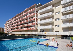 A multi-story hotel with a swimming pool, balconies, and a poolside area.