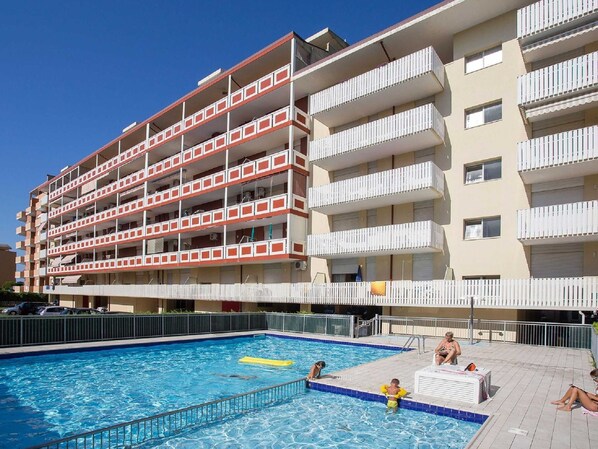 A multi-story hotel with a swimming pool, outdoor seating, and balconies.