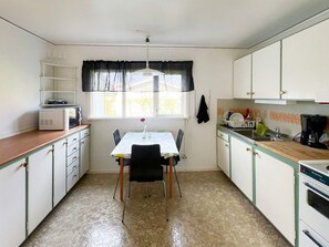 A compact kitchen with a dining table, chairs, a microwave, a coffee maker, and cabinets.