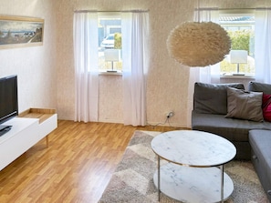 A modern living room with a wooden floor, a white sofa, a round marble coffee table, and a painting on the wall. - 6 Person Holiday Home in Mellbystrand (Mellbystrand)
