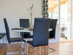 A dining area with a round table, four black chairs, and a vase with green plants. - 6 Person Holiday Home in Mellbystrand (Mellbystrand)